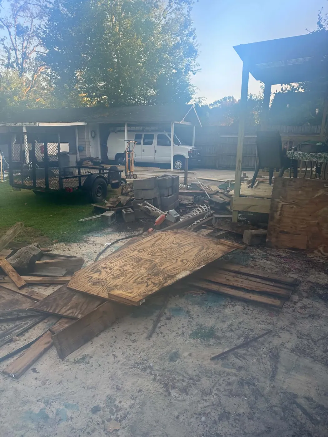 Residential outdoor area with lumber, debris, and equipment