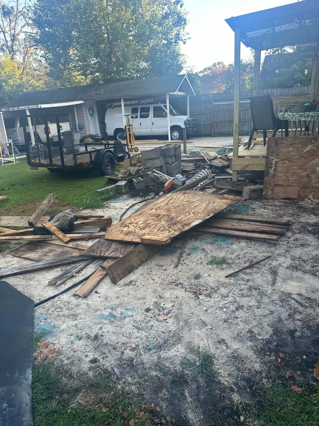 Residential outdoor area with debris, plywood, lumber, and equipment