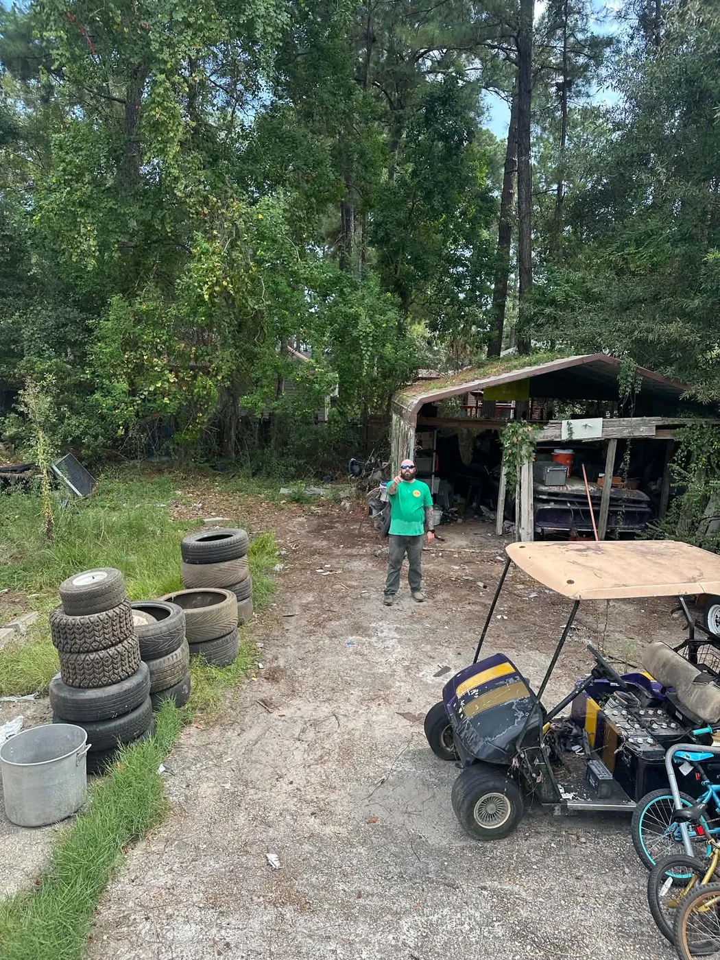 Wooded lot with tires, equipment, and miscellaneous items