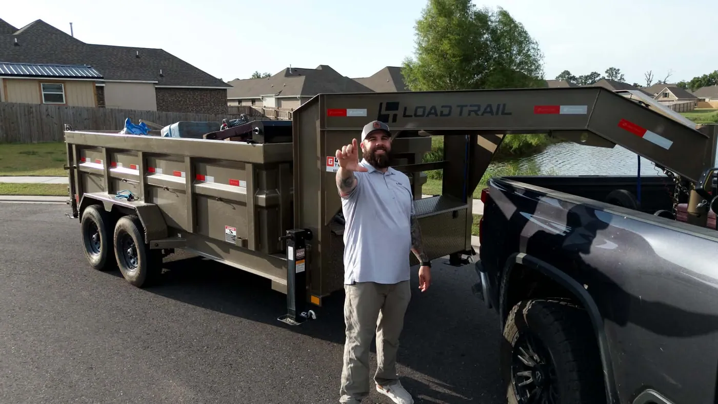 Garret standing beside a loaded dump trailer and pickup truck